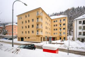 a yellow apartment building in a snow covered city at Boutique Apartment 23 in Jáchymov
