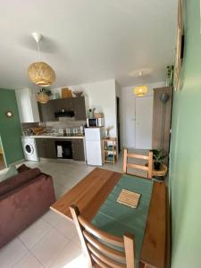 uma sala de estar com uma mesa de madeira e uma cozinha em Appartement centre-ville proche de Paris. em Limay