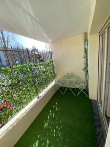 uma varanda com uma mesa e um relvado verde em Appartement centre-ville proche de Paris. em Limay