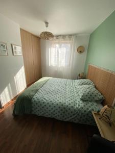um quarto com uma cama com um edredão verde em Appartement centre-ville proche de Paris. em Limay