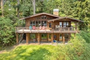 a large wooden house with people standing on the deck at Goss Lake Chalet by AvantStay Lakefront w Dock in Langley