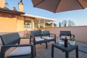 een terras met vier stoelen, een tafel en een parasol bij Casa Amedeo in Lucca