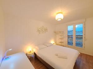 um quarto com uma grande cama branca e uma janela em Biarritz, terrasse vue Cathédrale em Reims