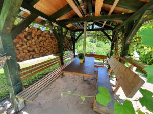 a wooden pavilion with benches and a pile of logs at Das grüne Haus am Hexenstieg in Rübeland