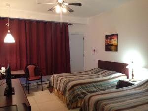 een slaapkamer met 2 bedden, een bureau en een rood gordijn bij Motel Econonuit in Sherbrooke