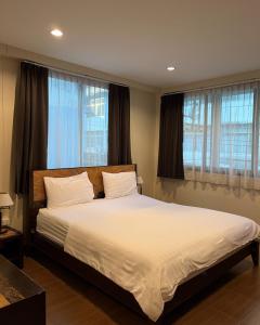 Baan Glang Soi في بانكوك: غرفة نوم بسرير وملاءات بيضاء ونوافذ