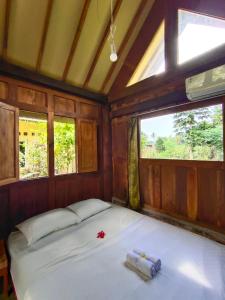 a bed in a room with two windows at Mettaloka Guesthouse in Magelang