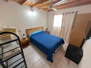 een slaapkamer met een bed met een blauwe deken en een raam bij Tony Center III in Las Toninas