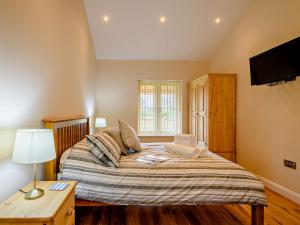 a bedroom with a bed with a tv on the wall at 3 Bed in Wroxham 83034 in Worstead