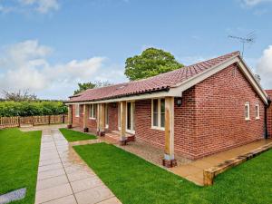 a red brick house with a green lawn at 3 Bed in Wroxham 83034 in Worstead