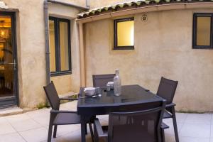 ein schwarzer Tisch und Stühle mit einer Flasche drauf in der Unterkunft Appartement avec cour privée + clim séjour + wifi in Avignon