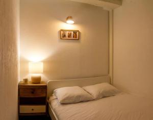ein Schlafzimmer mit einem Bett und einem Nachttisch mit einer Lampe in der Unterkunft Appartement avec cour privée + clim séjour + wifi in Avignon