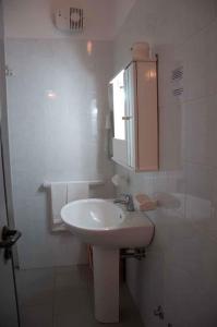 bagno bianco con lavandino e armadietto di Hotel Villaggio Aurora a San Pietro in Bevagna