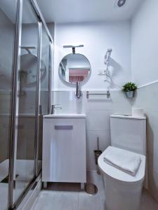 a white bathroom with a toilet and a mirror at Hostal A Nuestra Senora de La Paloma in Madrid