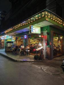 a restaurant with people sitting at tables outside at night at Baan Glang Soi in Bangkok