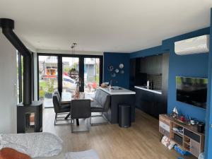 uma sala de estar com uma cozinha com paredes azuis em The Waterlodge Heeg - inclusief sloep en zeilboot em Heeg