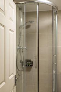 La salle de bains est pourvue d'une douche et d'une porte en verre. dans l'établissement South Kensington Courtfield Gardens studio, à Londres