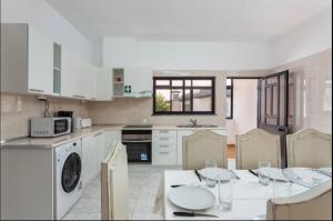 a kitchen with a table and chairs and a kitchen with white cabinets at Aerya private rooms in Faro