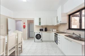uma cozinha branca com um lavatório e uma máquina de lavar louça em Aerya private rooms em Faro
