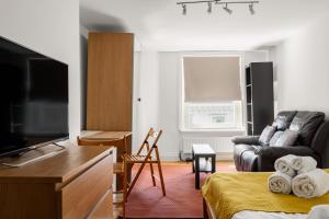 - un salon avec un canapé et une télévision dans l'établissement South Kensington Courtfield Gardens studio, à Londres