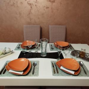 una mesa con platos naranjas y servilletas. en Family Star apartman en Čačak
