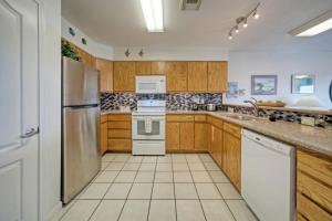 a kitchen with wooden cabinets and stainless steel appliances at Salt Sun by AvantStay Beach Access Pool in Port Aransas