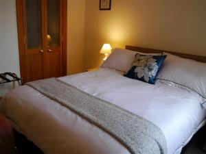 un grande letto bianco con un cuscino blu sopra di Number 48 a Dumfries