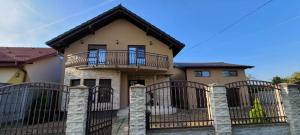ein Haus mit einem Zaun und einem Balkon in der Unterkunft American Stay in Buziaş