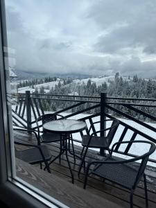 uma mesa e cadeiras numa varanda com neve no chão em Мелодія Гір .Апартаменти з видом на гори . em Vorokhta