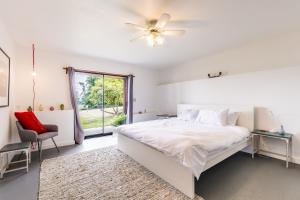 ein weißes Schlafzimmer mit einem Bett und einem Fenster in der Unterkunft Camano Vista Paradise by AvantStay Private Beach in Greenbank
