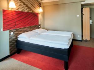 ein kleines Bett in einem Zimmer mit einem roten Teppich in der Unterkunft B&B Hotel Frankfurt-Messe in Frankfurt am Main