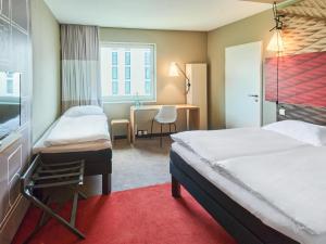 um quarto de hotel com duas camas e uma secretária em B&B Hotel Frankfurt-Messe em Frankfurt