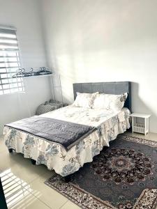 un letto in una camera bianca con un tappeto di Casa D JR Homestay a Ipoh