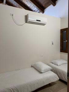 a bedroom with two beds and a air conditioner on the wall at Cottage in Center of Historic Zichron Yaakov in Zikhron Ya'akov