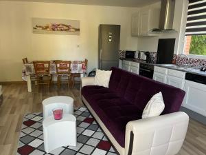 a living room with a purple couch in a kitchen at Maison « jardin la cigogne » in Sainte-Croix-en-Plaine