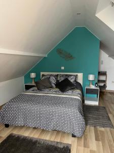 a bedroom with a large bed with a blue wall at Maison « jardin la cigogne » in Sainte-Croix-en-Plaine