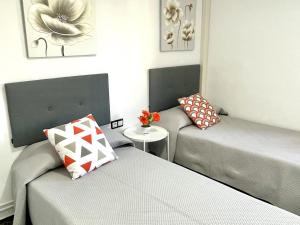 a room with two beds and a table with flowers at APARTBEACH EL CARRILET CENTRICO y LUMINOSO in Reus