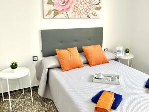 a bed with orange pillows and a tray on it at APARTBEACH EL CARRILET CENTRICO y LUMINOSO in Reus