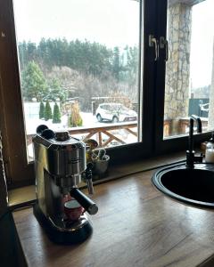 eine Kaffeemaschine auf einer Theke neben einem Fenster in der Unterkunft Ранчо, Дом для релакса в окружении леса и озёр in Kolonshchina