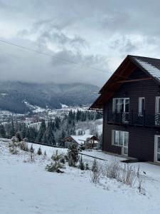 dom na szczycie pokrytego śniegiem wzgórza w obiekcie Мелодія Гір Вид на гори w mieście Worochta