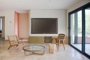 a living room with a flat screen tv and chairs at Villa des jacinthes in Tarascon