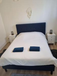 ein weißes Bett mit zwei blauen Kissen darauf in der Unterkunft Appart'hotel SOLESMES in Solesmes