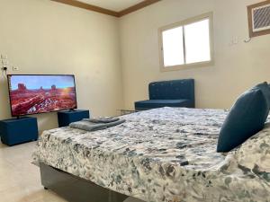 a bedroom with a bed and a flat screen tv at ستوديو كبير غرفة و حمام بمكيف غسالة تلفاز واي فاي in Al-Salam