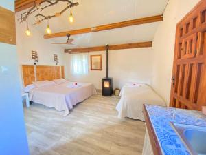 a room with two beds and a stove in it at Cabañas Rústicas dentro de la Finca El Castillo in La Cabrera