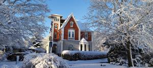 a house covered in snow with trees and bushes at Villa Kunterbunt, Gemütlichkeit am Waldesrand in Drangstedt