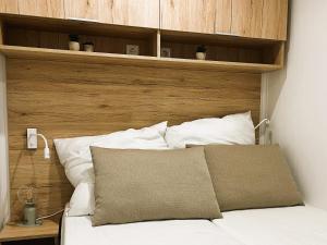 un letto con testiera in legno e cuscini bianchi di Ostseecamp Ferienhaus "Quartier 104" a Scharbeutz