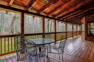 une terrasse couverte avec une table et des chaises. dans l'établissement Twin Creeks Lodge by AvantStay 33 Acre Retreat, à Brevard