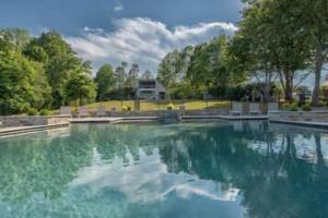 een zwembad met bomen en een huis bij Azalea Retreat- The Lodge by AvantStay Best View in Lake Norman of Catawba