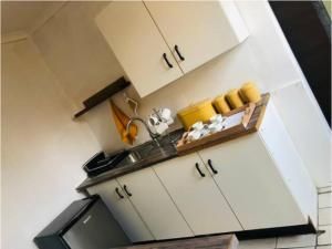uma cozinha com armários brancos e um lavatório em Serenity Cottage em Benoni