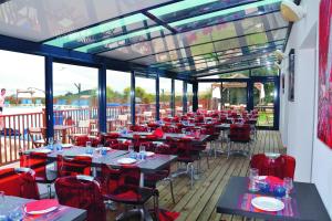 a restaurant with tables and red chairs on a deck at VVF Belle-Île-en-Mer in Le Palais +31 photos